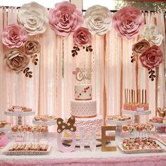 a table topped with lots of cakes and desserts covered in paper flowers on top of it