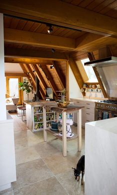 a kitchen with an oven, stove and sink in the middle of two floors that have wooden beams on them