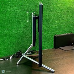 an office desk with a computer monitor and keyboard on it, in front of a green wall