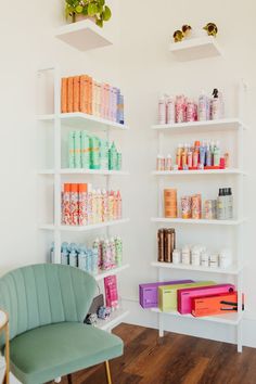 a room with shelves filled with lots of different items and containers on the wall next to a green chair