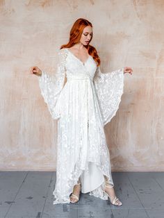 a woman in a white dress standing against a wall