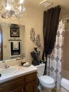 a white toilet sitting next to a bath tub under a chandelier in a bathroom