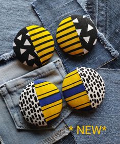 three yellow and black buttons sitting on top of some blue jean pants with holes in them