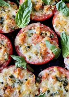 several tomatoes with cheese and spinach leaves on top