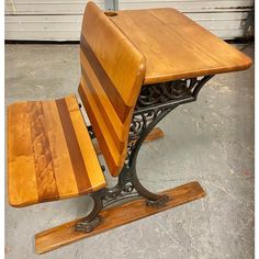 a wooden table and bench sitting on top of a metal stand in front of a garage door