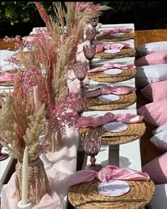 the table is set up with pink and white linens, wicker baskets, vases filled with dried flowers