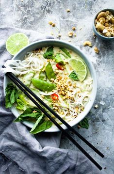 a bowl filled with noodles and vegetables next to two chopsticks on a table