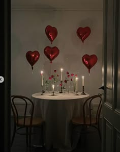 the table is set with candles and heart shaped balloons