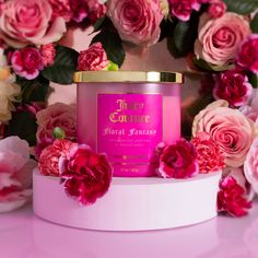 a pink candle sitting on top of a white box surrounded by flowers and greenery