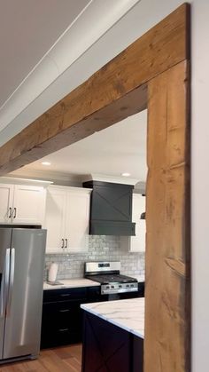 a kitchen with black and white cabinets, stainless steel appliances and wood beams in the ceiling