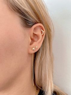 a woman wearing gold ear cuffs with two small stars on the back of her ear