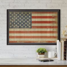 an american flag is hanging on the wall above a table with books and a coffee mug