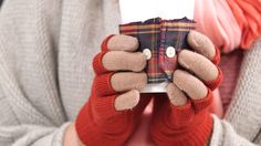 a person wearing red gloves holding up a cell phone