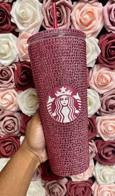 the starbucks cup is in front of pink and white roses with a red straw lid