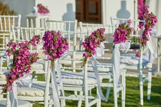 rows of white chairs with pink flowers on them and ribbons tied to the back of each chair