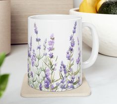 a coffee mug with lavender flowers painted on the side and lemons in the background