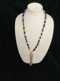 This necklace is made from multicolored beads and it has a tassel at the front. The tassel has a gold ball and the multicolored fronds hanging from it. It measures 30 inches and the tassel measures 5 inches. Multicolor Beaded Tassel Necklace For Festivals, Hand-strung Multicolor Beaded Lariat Necklace, Adjustable Multicolor Tassel Necklace With Colorful Beads, Adjustable Multicolor Beaded Necklaces With Tassels, Adjustable Multicolor Beaded Tassel Necklace, Multicolor Beaded Necklaces With Dangling Beads, Multicolor Dangling Beaded Necklace, Adjustable Long Tassel Necklace With Dangling Beads, Adjustable Multicolor Tassel Necklace With Round Beads