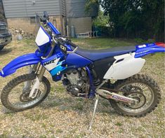 a blue and white dirt bike parked in the grass