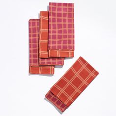 four orange and pink plaid napkins laying on top of each other in front of a white background