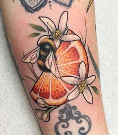 a close up of a person's leg with tattoos on it and a bee