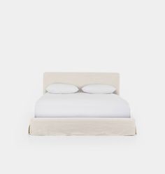 a white bed with two pillows on top of it