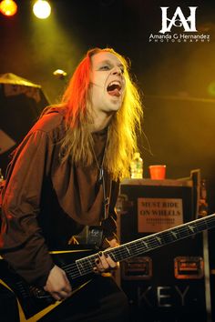 a man with long hair playing an electric guitar