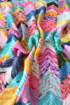 a multicolored crocheted blanket on top of a bed