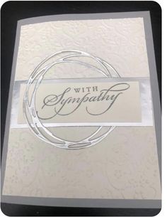 a white card with the words sympathy written in cursive writing, and a silver circle