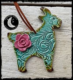 a ceramic dog ornament with a pink rose on it's back end