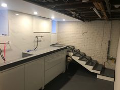 an empty kitchen with stairs leading up to the counter top and below it is a white brick wall