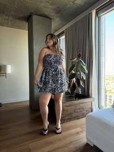 a woman is standing in front of a window and looking at the city from her bedroom