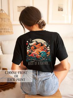 This stunning t-shirt showcases a striking and stylized illustration of a flock of migratory birds in flight, capturing their sense of freedom and adventure.  Did you know that migratory birds have the ability to navigate using a range of cues, including the position of the sun, the Earth's magnetic field, and even the stars? It's an incredible feat of navigation, and one that continues to amaze scientists and bird enthusiasts alike. This t-shirt is the perfect choice for anyone who loves nature Artistic Graphic Print Top As A Gift, Artistic Graphic Print Tops As Gift, Artistic Graphic Print Top As Gift, Black Printed T-shirt For Fan Merchandise, Black Band Merch Printed T-shirt, Black Printed Band Merch T-shirt, Vintage Black Printed T-shirt, Graphic Tee With Graphic Design As Gift, Graphic Tee With Graphic Design For Gift