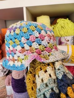 a multicolored crocheted hat sits on top of a pile of yarn