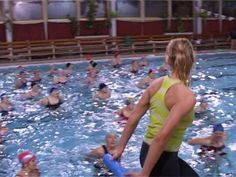 a group of people in a swimming pool with one person holding a water bottle and the other is wearing a life preserver