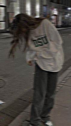 a person riding a skateboard on a city street at night with their hair blowing in the wind