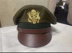 an army green and brown hat sitting on top of a white tablecloth covered table