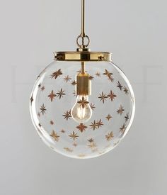 a clear glass globe light with gold stars on the bottom and an antique brass finish