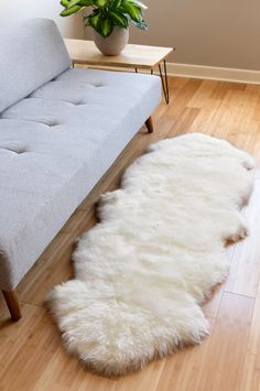 a white sheepskin rug on the floor next to a couch