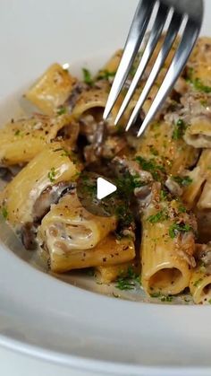 a fork is stuck into some pasta with mushrooms