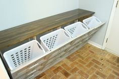 a row of white laundry baskets sitting on top of a wooden shelf