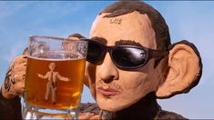 a man with sunglasses holding up a beer in front of his face and another statue behind him