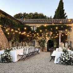 an outdoor dining area with tables, chairs and lights strung from the building's roof