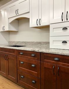 a kitchen with white cabinets and marble counter tops