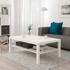 a living room filled with furniture and a white coffee table in front of a gray couch