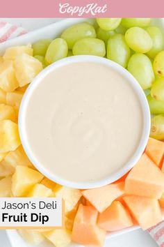 a white plate topped with grapes and cheese next to a bowl of fruit dipping sauce