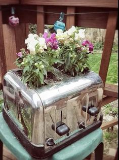 an old toaster with flowers growing out of it sitting on top of a chair