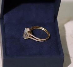 an engagement ring sits in a blue velvet box