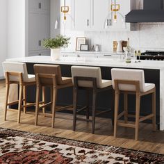 a kitchen with an island and bar stools in front of the countertop area