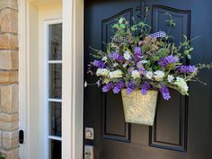 a flower pot hanging on the side of a door with purple and white flowers in it