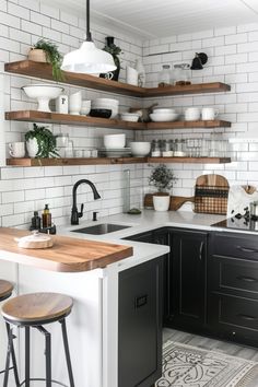 a kitchen with black cabinets and white subway backsplash, open shelving above the sink